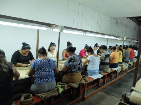 Frauen arbeiten in einer Werkstatt an handwerklichen Projekten an langen Tischen.