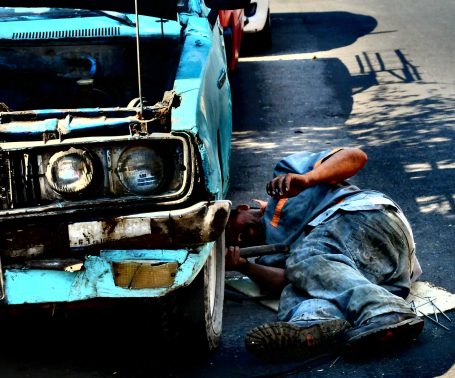 Ein Mechaniker arbeitet unter einem blauen Auto und repariert dessen Motor.