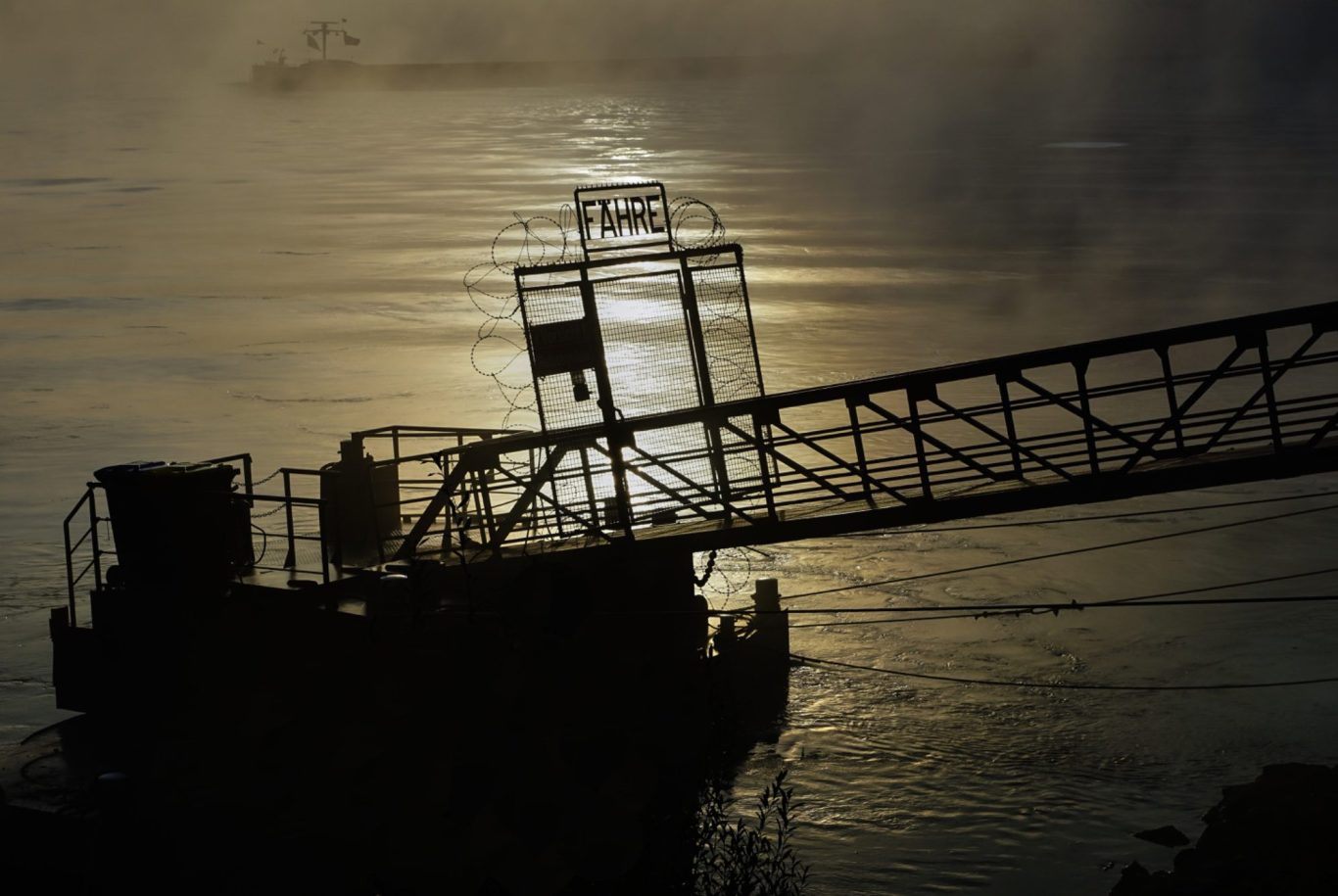Rote Holzstruktur auf Wasser mit Bergen im Hintergrund und klarem Himmel.