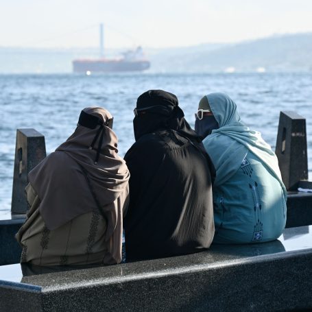 Frauen sitzen auf einer Kaimauer